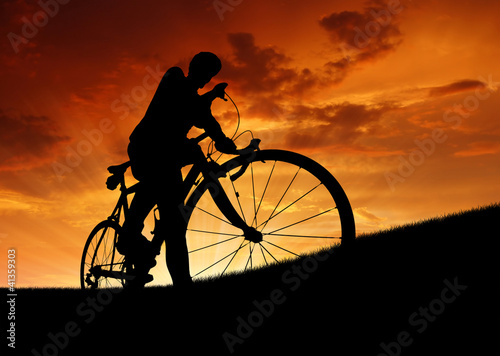 Photo: silhouette of the cyclist on road bike at sunset silhouette of the cyclist on road bike at sunset