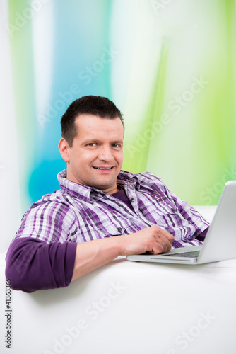 Foto: freundlicher mann sitzt bequem am laptop freundlicher mann sitzt bequem am laptop