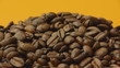 A pile of roasted coffee beans rotating on orange background