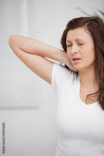 Photo: Woman touching her painful neck Woman touching her painful neck