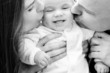 parents kissing smiling baby
