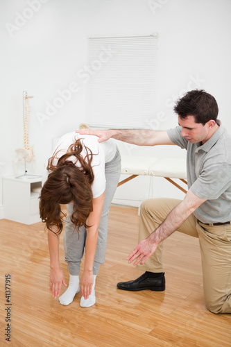 Photo: Doctor looking at a patient who is doing stretching exercises Doctor looking at a patient who is doing stretching exercises