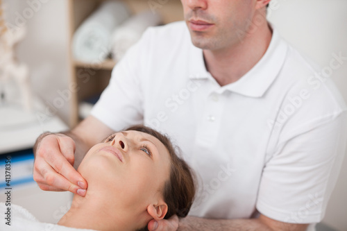 Photo: Physiotherapist pressing two fingers on the neck of his patient Physiotherapist pressing two fingers on the neck of his patient