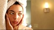 Mixed race woman applying lotion to her face
