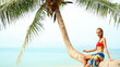 Adorable woman in red bikini resting on palm tree at the beach