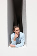 Man leaning out of a building into the sunshine