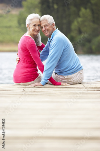 Photo: Romantic senior couple sitting on a jetty Romantic senior couple sitting on a jetty
