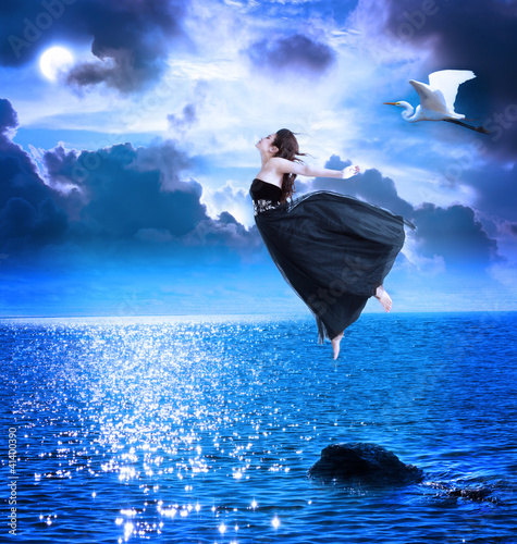 Photo: Beautiful girl jumping into the blue night sky Beautiful girl jumping into the blue night sky