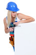 Blond builder holding power drill and blank message board