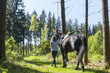 Reiterin führt Pferd im Wald