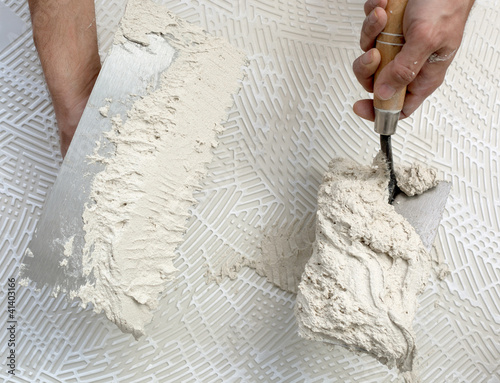 Photo: notched trowel and worker hands on tile notched trowel and worker hands on tile