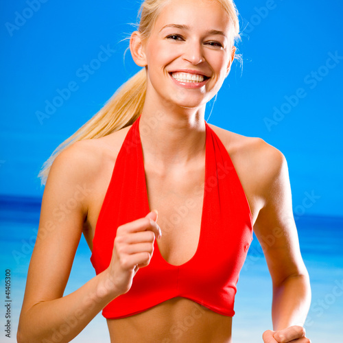 Photo: Young happy woman running on beach Young happy woman running on beach
