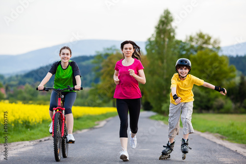 Photo: Active family - mother and kids running, biking, rollerblading Active family - mother and kids running, biking, rollerblading