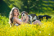 Happy and attractive teen girl playing with dogs in green field