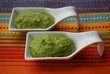 Green broad beans cream in white china dish on orange background Green broad beans cream in white china dish on orange background
