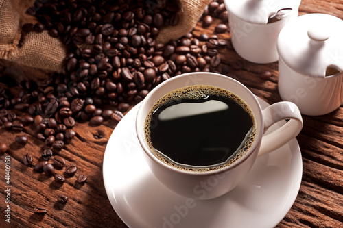 Foto: Coffee cup with burlap sack of roasted beans Coffee cup with burlap sack of roasted beans