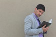 Photo: A businessman is reading a book while leaning on a wall A businessman is reading a book while leaning on a wall