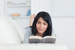 Woman reading a book while lying on a couch