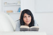 Woman holding a book while laying on a sofa