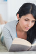 Woman reading a book while resting on a couch