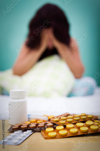 Photo: Pills and out of focus sick or depressed woman Pills and out of focus sick or depressed woman