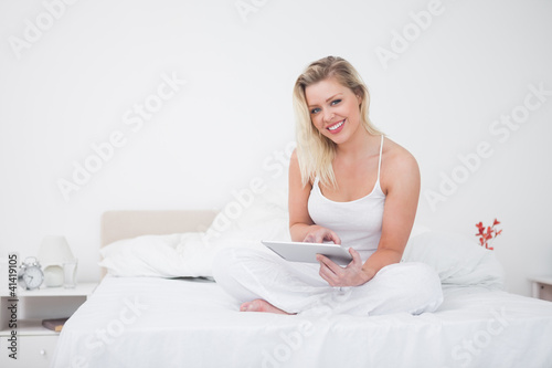Foto: Blonde using an ebook reader while sitting Blonde using an ebook reader while sitting