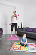 A young mother exercising at home with her baby