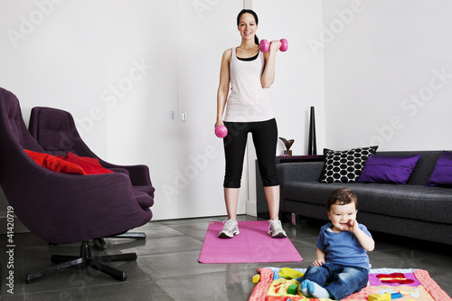 Photo: A young mother exercising at home with her baby A young mother exercising at home with her baby