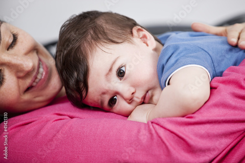Photo: A mother cuddling her baby son on a sofa, close up A mother cuddling her baby son on a sofa, close up