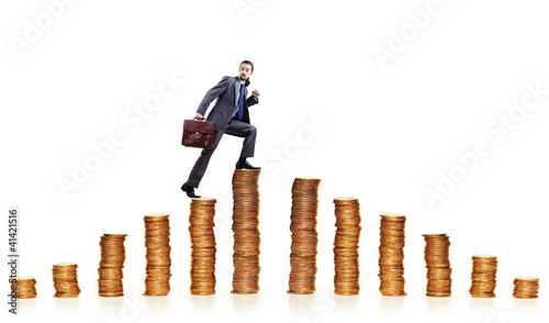 Photo: Businessman climbing gold coins stacks Businessman climbing gold coins stacks