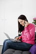A woman using a laptop and talking on a mobile phone at home