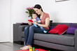 A mother and her baby son sitting on the sofa, reading a book