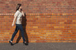 Foto: Woman walk by the wall & talking on the phone Woman walk by the wall & talking on the phone