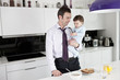 A father trying to use the telephone whilst holding his baby son