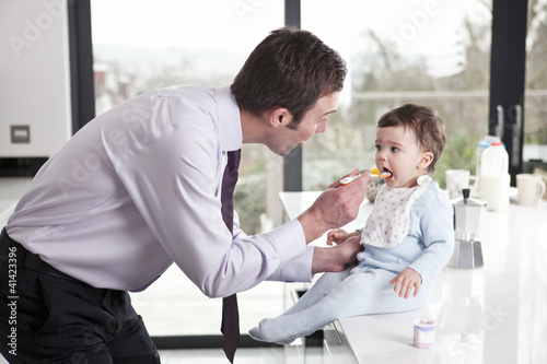 Photo: A father feeding his baby son breakfast A father feeding his baby son breakfast
