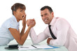 A couple of businesspeople arm wrestling.
