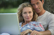 Couple sat in the park with laptop