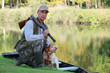 A hunter and his dog by a river.