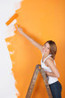 lächelnde frau streicht eine wand orange