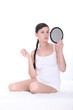 Young woman sat on bed holding mirror