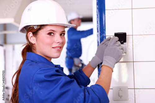 Photo: Young female electrician wiring a building Young female electrician wiring a building