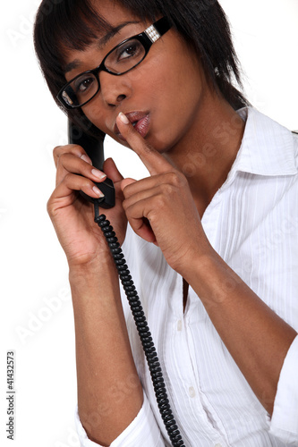 Foto: woman on the phone making a sign for silence woman on the phone making a sign for silence