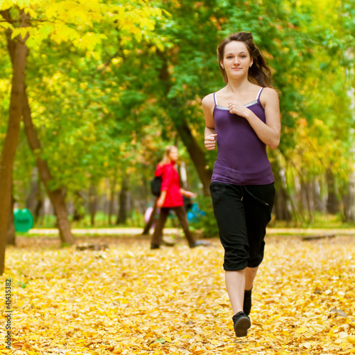 Photo: A young girl running in autumn park A young girl running in autumn park