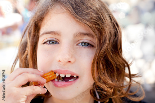 Photo: Blue eyes little girl eating churros fried crullers Blue eyes little girl eating churros fried crullers