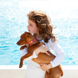 brunette kid girl with dog on the sea