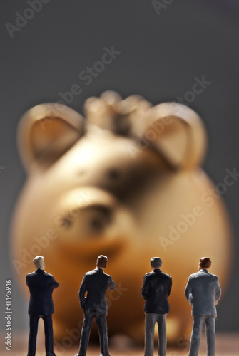 Photo: Banker vor einem goldenen Sparschwein Banker vor einem goldenen Sparschwein