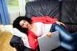 Sleeping woman holding laptop lying on a sofa