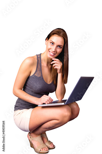 Photo: Smiling girl on laptop sitting on haunches Smiling girl on laptop sitting on haunches