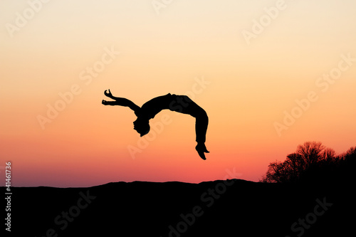 Photo: silhouette of gymnast doing a backflip in sunset silhouette of gymnast doing a backflip in sunset