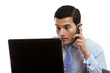 Man at computer making or receiving phone call